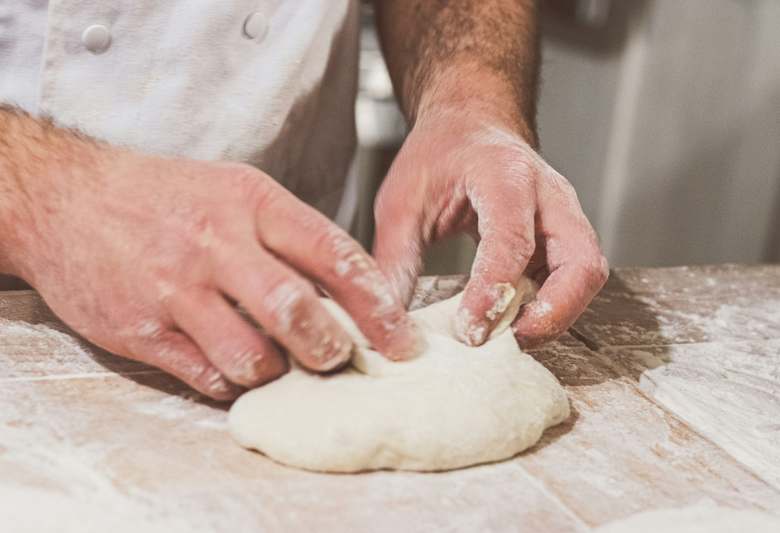 Hand placing freshly baked loaf into a bread machine for testing